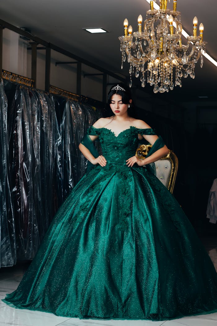 Stunning emerald green ball gown displayed in a luxurious boutique setting with chandelier lighting.