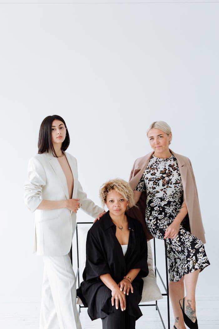 about-us Three women in stylish outfits pose confidently in a studio setting with a white background.